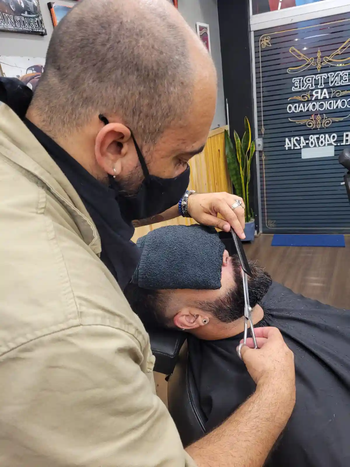 Barbeiro desenhando o contorno da barba com navalha, em detalhe.