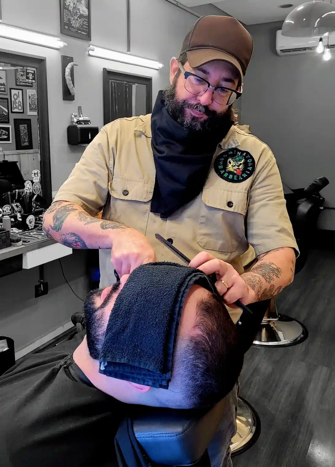 Toalha quente aplicada no rosto do cliente antes de fazer a barba.