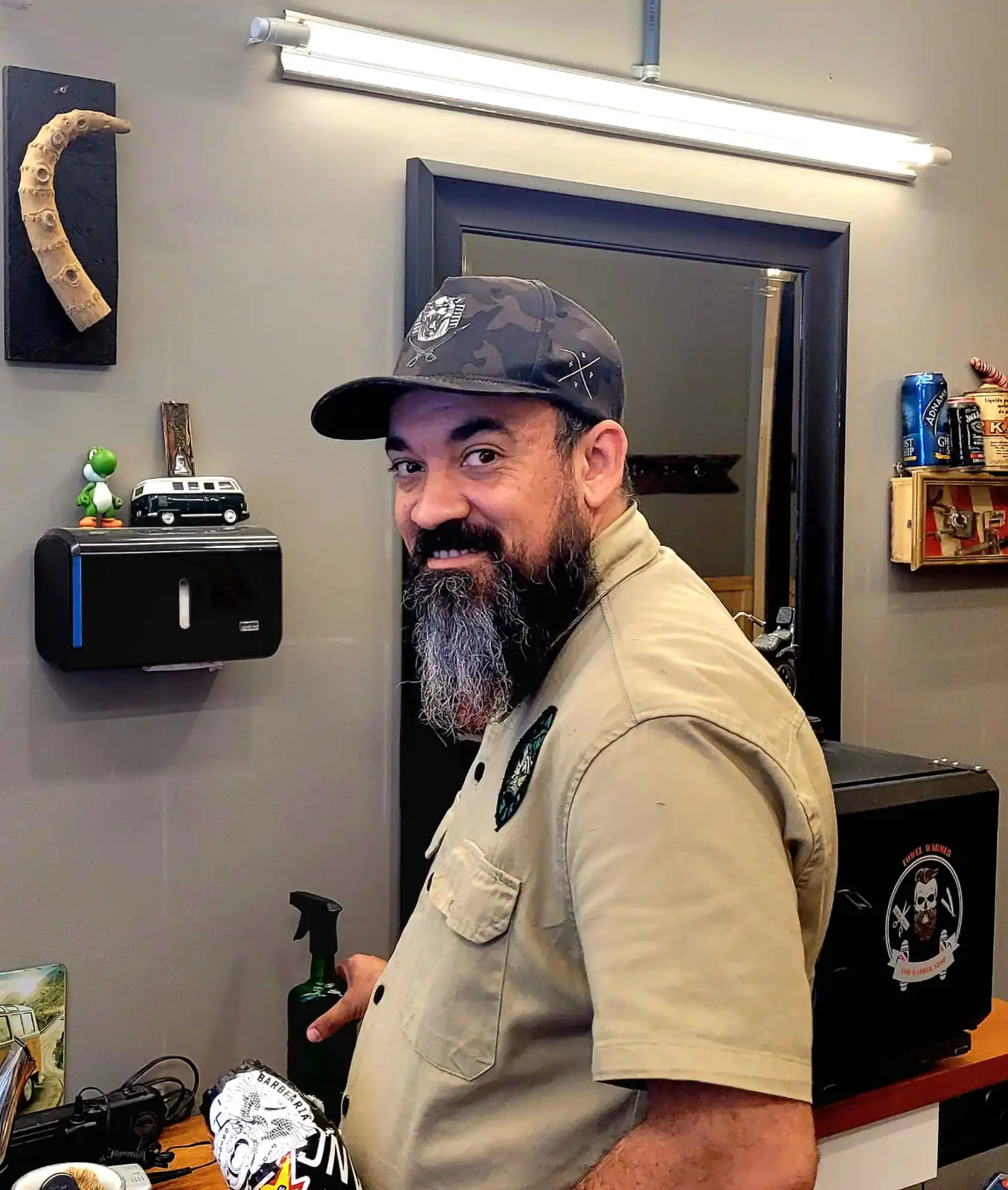 Hugo Panda, barbeiro da Dominato, de boné e camisa da barbearia, no salão.