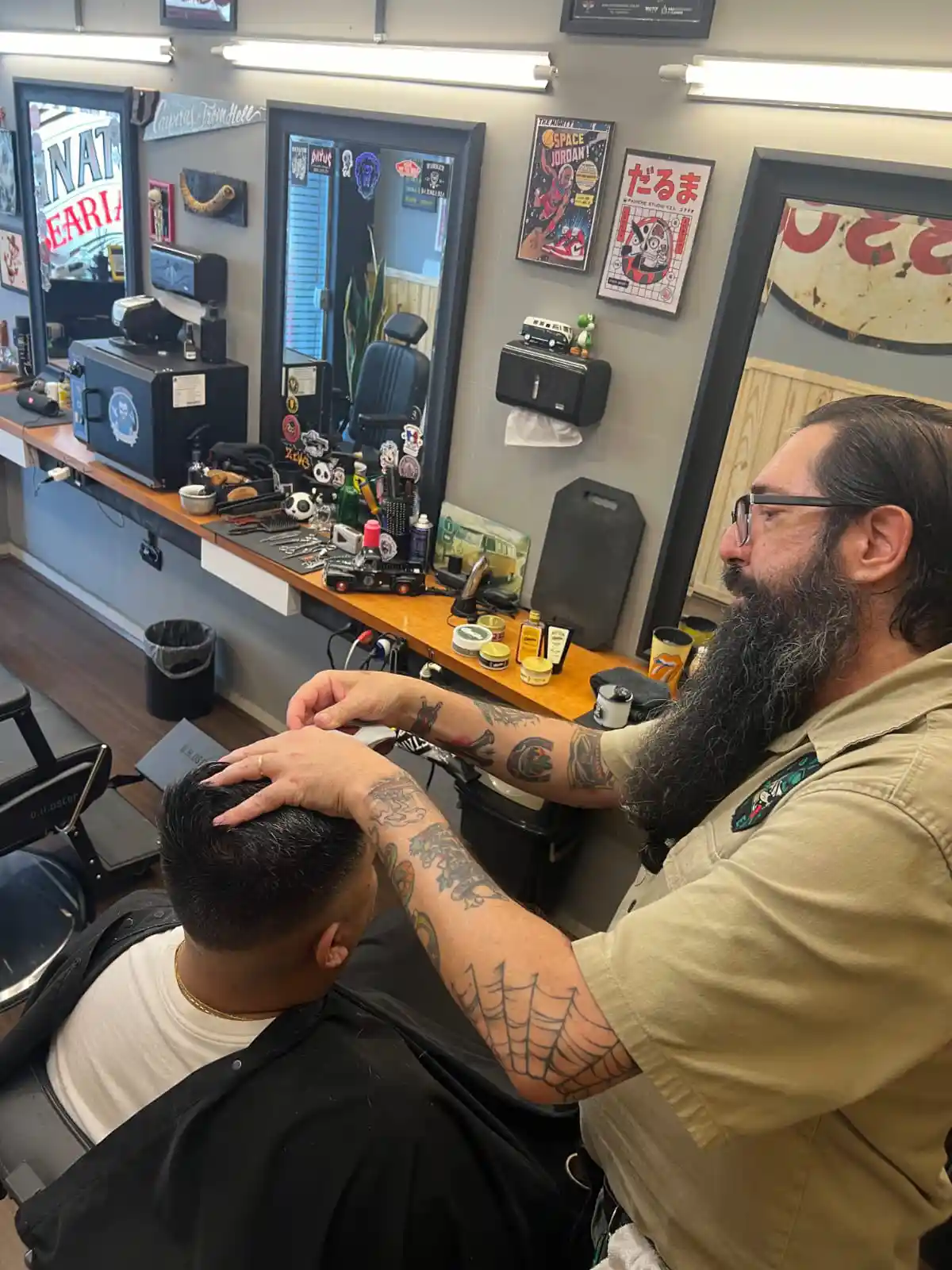 Barbeiro cortando o cabelo de um cliente em frente ao espelho.